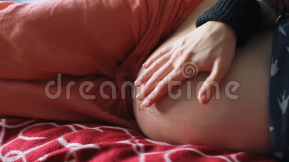 接近未来的母亲用手抚摸她怀孕的肚子在床上安慰和拥抱她的孩子在里面视频的预览图