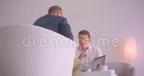两位商人在办公室里坐在扶手椅上开会的特写照片视频的预览图