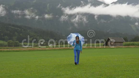 一个年轻的女人在雨下走在农村视频的预览图