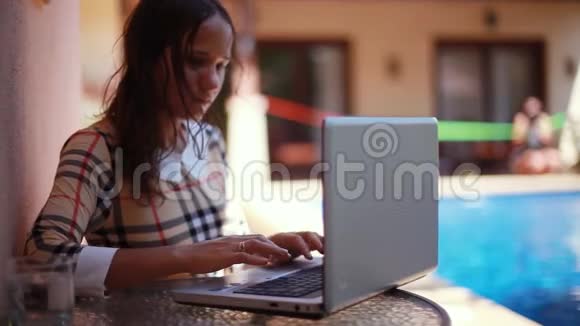 漂亮的黑发女人坐在池边用她的笔记本电脑工作年轻女性模式自由应聘视频的预览图
