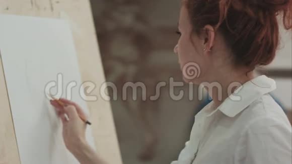 年轻女子用画架用铅笔画画并讲解过程视频的预览图