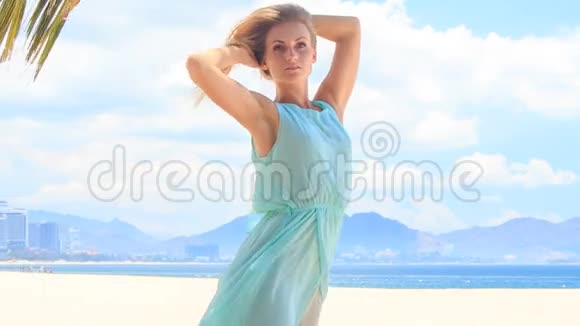 蔚蓝的金发女孩在沙滩上迎风挽起头发视频的预览图