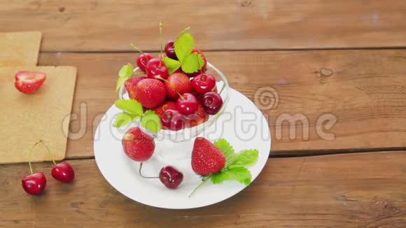 放在木桌上的白色盘子上是草莓和樱桃视频的预览图