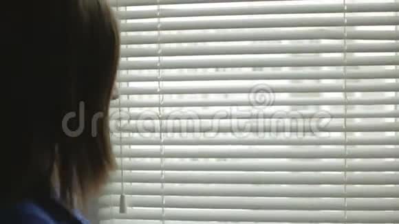 一位怀孕的年轻女子站在窗户前关上了百叶窗视频的预览图