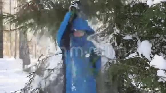 在阳光明媚的日子里少年从树枝上扔雪视频的预览图