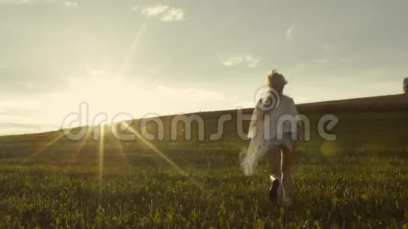 运动的女孩跑到明亮的日落绿色的草坪和自由的空间周围慢动作生命的美丽视频的预览图