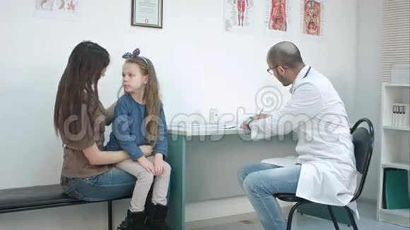 小女孩亲吻她的妈妈微笑的男医生给她糖果的良好行为视频的预览图