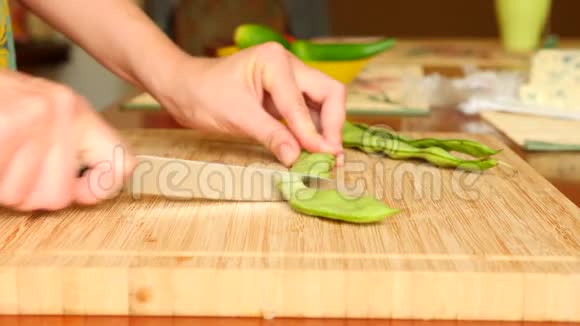 女用手拿刀在木板上剪了一串豆子4k慢动作视频的预览图