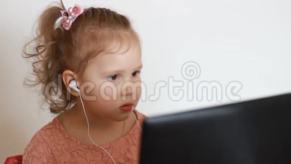 女孩戴着耳机看着屏幕监视器电脑视频的预览图