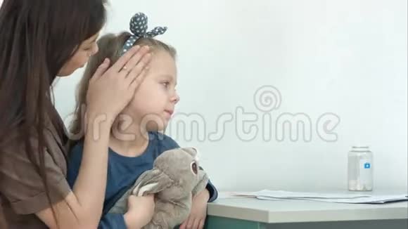 妈妈抱着小女孩在医生办公室用体温计给她量体温视频的预览图