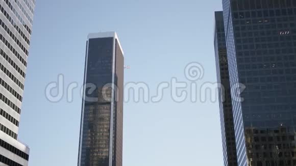 飞机飞过洛杉矶市中心的摩天大楼城市市中心带太阳的现代玻璃反光摩天大楼视频的预览图