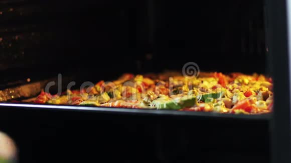 女人打开烤箱的门拿出烘焙的原始意大利披萨关闭4k视频的预览图