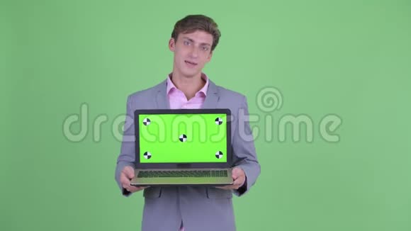 快乐的年轻商人一边说话一边展示笔记本电脑视频的预览图