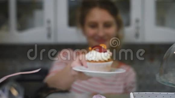 一个梳着马尾辫的姑娘穿着一件鲜艳的条纹衬衫双手捧着漂亮的蛋糕视频的预览图