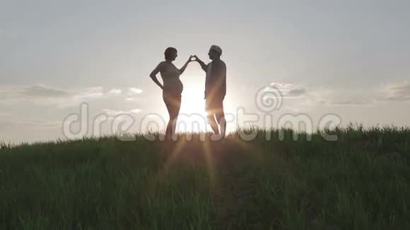 一对相爱的夫妇在明亮的阳光下用手指做心脏视频的预览图
