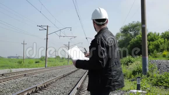 铁路交通检查员在对讲机上烦躁地交谈戴着蓝图计划的白盔铁路工人视频的预览图