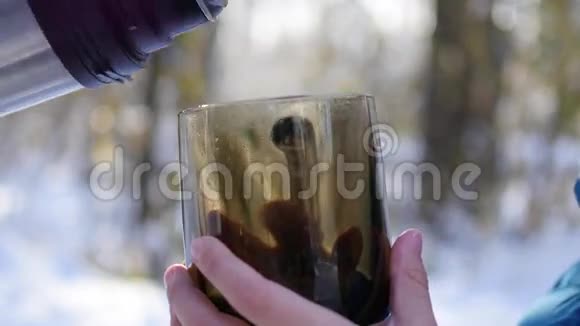在寒冷的晴天茶从热水瓶里倒进杯子里视频的预览图