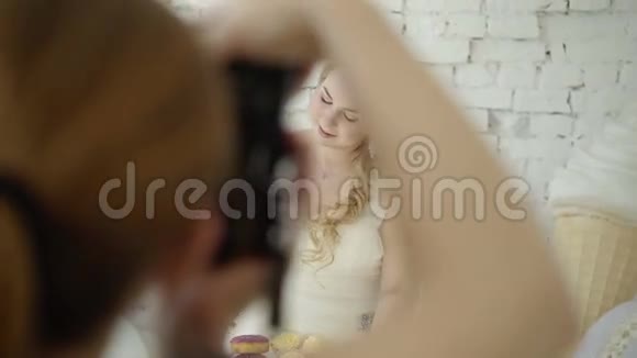 可爱的金发女郎穿着婚纱摆着糖果摆在工作室里视频的预览图