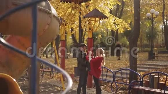 年轻幸福的家庭带着一个孩子在操场上公园里的秋千和旋转木马视频的预览图