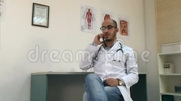 年轻的男医生用手机说话看着手表视频的预览图