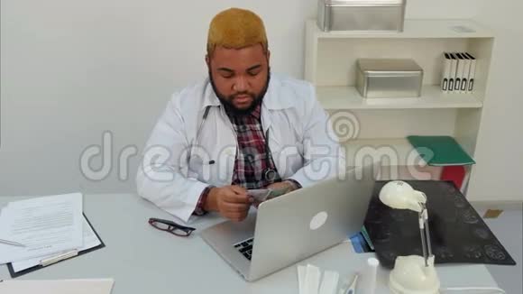 年轻的美国黑人男医生在他的办公桌上数钱视频的预览图