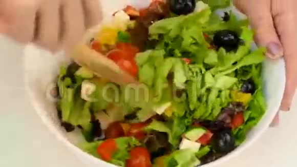 女性手把沙拉混合在一个大的白色碗里视频的预览图