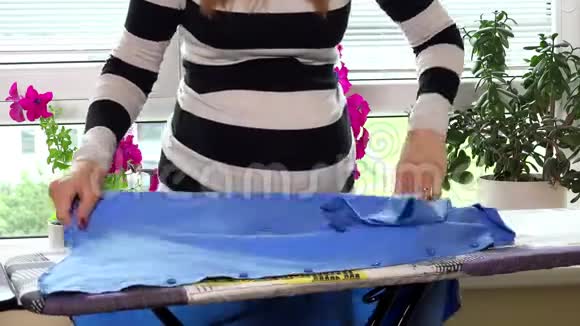 怀孕女性妻子用蒸汽熨衣板烫丈夫的衬衫视频的预览图