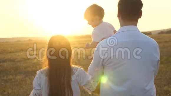 日落时分爸爸和妈妈和她的女儿抱在怀里散步一家人在日落时带着一个孩子散步有女儿的父亲视频的预览图