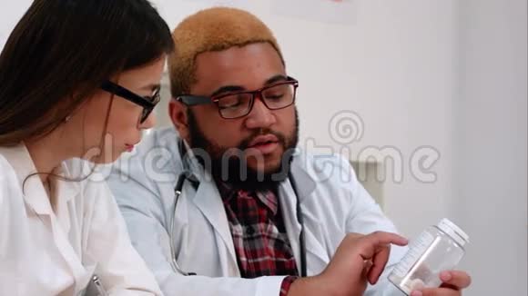 非裔美国男医生拿着一罐药丸护士一边做笔记视频的预览图