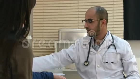 戴眼镜的年轻医生向母亲和孩子解释诊断视频的预览图