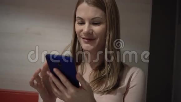 漂亮的年轻女人在咖啡馆里用她的智能手机浏览互联网与朋友交流视频的预览图