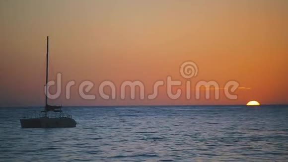 夏日夕阳西下的海景宁静的沙滩海浪带着小船在天边航行视频的预览图