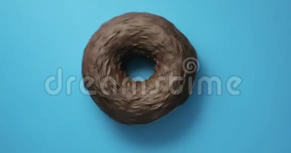 巧克力山核桃甜甜圈特写镜头旋转蓝色背景美味的甜面圈在盘子上旋转顶级视频的预览图