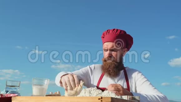 胡子厨师在新鲜空气中做饭面包师烤面包面包师揉面团视频的预览图