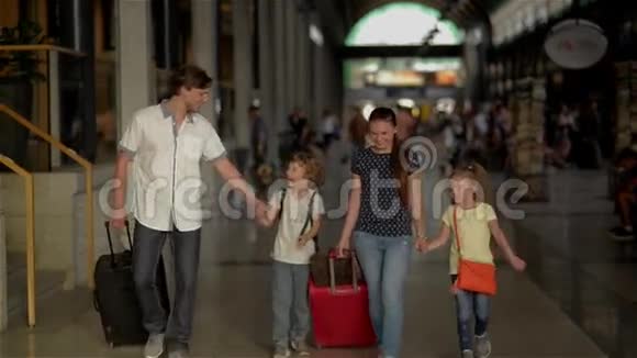 有孩子的幸福家庭去火车站父母和孩子在机场旅行和步行视频的预览图