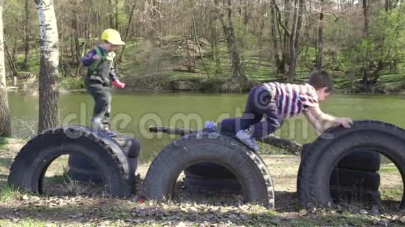 两个孩子一起玩跳着爬在轮胎上视频的预览图