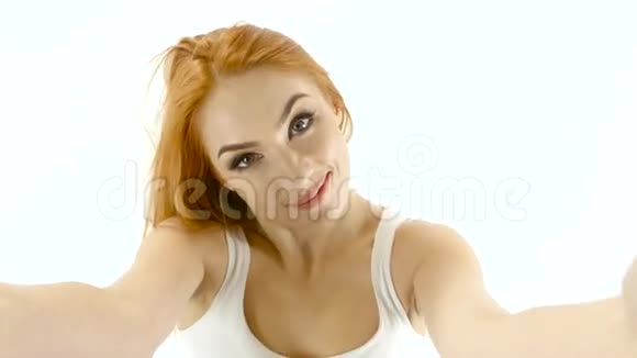 红头发的女孩在相机上摆姿势自拍白色背景特写视频的预览图
