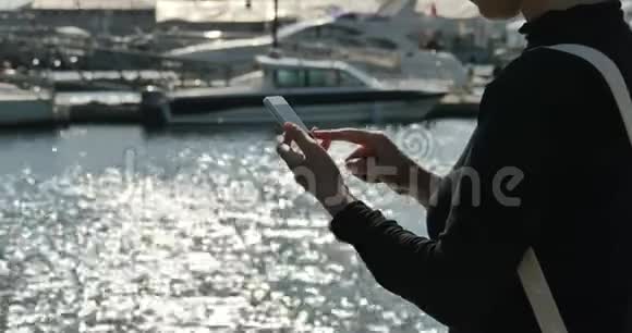 一个女孩在海边使用智能手机游艇和在港口航行视频的预览图