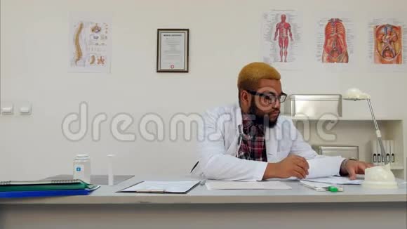 在办公室处理医疗表格和文件的非裔美国医生视频的预览图