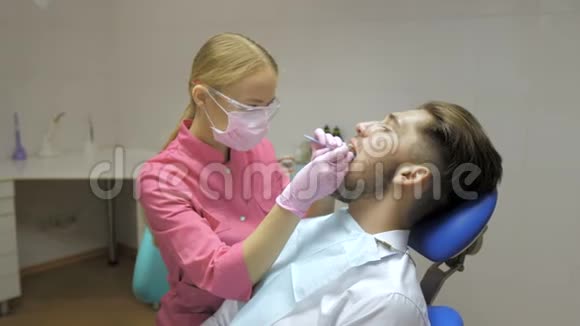 女性牙医男性病人在牙科中清洁牙齿视频的预览图