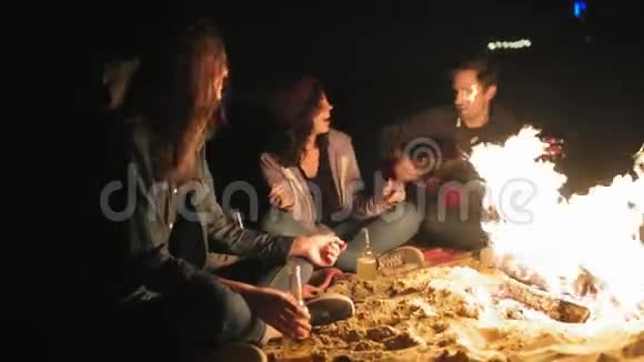 年轻开朗的人深夜坐在篝火旁弹吉他唱歌喝啤酒快乐视频的预览图