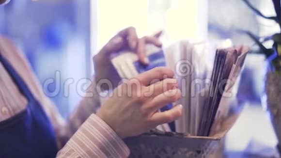 一个女售货员为一束花选择包装纸的侧视图视频的预览图