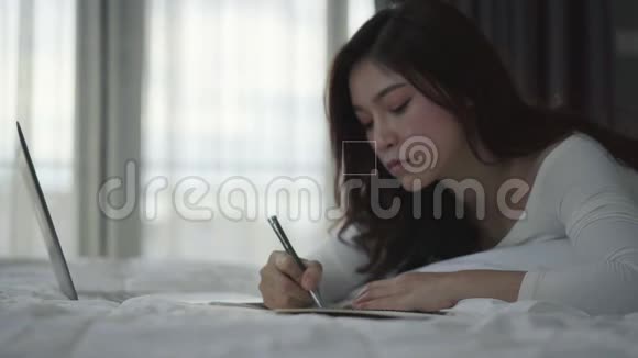 女人在床上写笔记本电脑视频的预览图