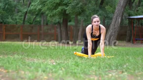 体育运动中的年轻运动员妇女参与健身躺在草坪上的公园里的地毯上视频的预览图