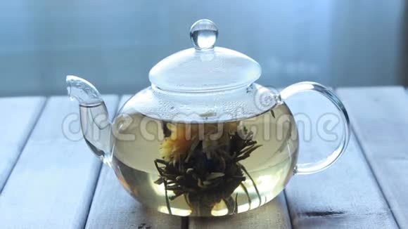 窗前的木制背景上有一个玻璃茶壶和中国花茶的视频视频的预览图
