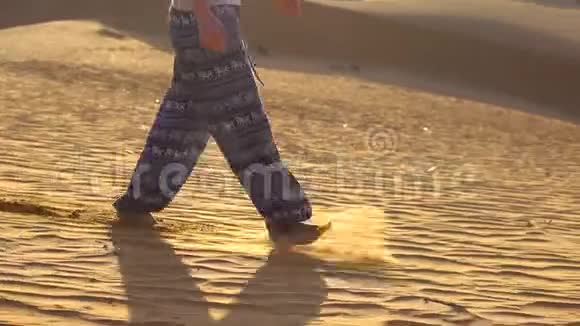 穿着亚洲裤子的年轻女孩在越南梅内的红色沙漠中漫步视频的预览图