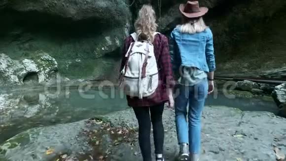两位年轻的高加索女性旅行者沿着一个热带洞穴旅行背上行军背包灵感来自于视频的预览图