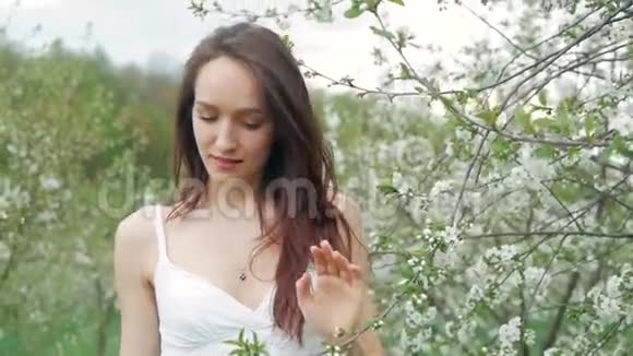 春天的时尚肖像一位美丽快乐的年轻女子穿着白色连衣裙棕色长发奔跑享受花香视频的预览图