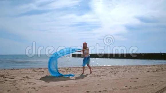 孕妇在风中飘着蓝色的布玩乐孕妇海滩视频的预览图