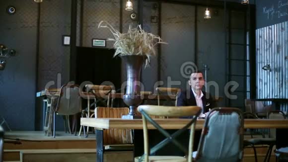 年轻的商人坐在咖啡馆的桌子旁等待服务员视频的预览图